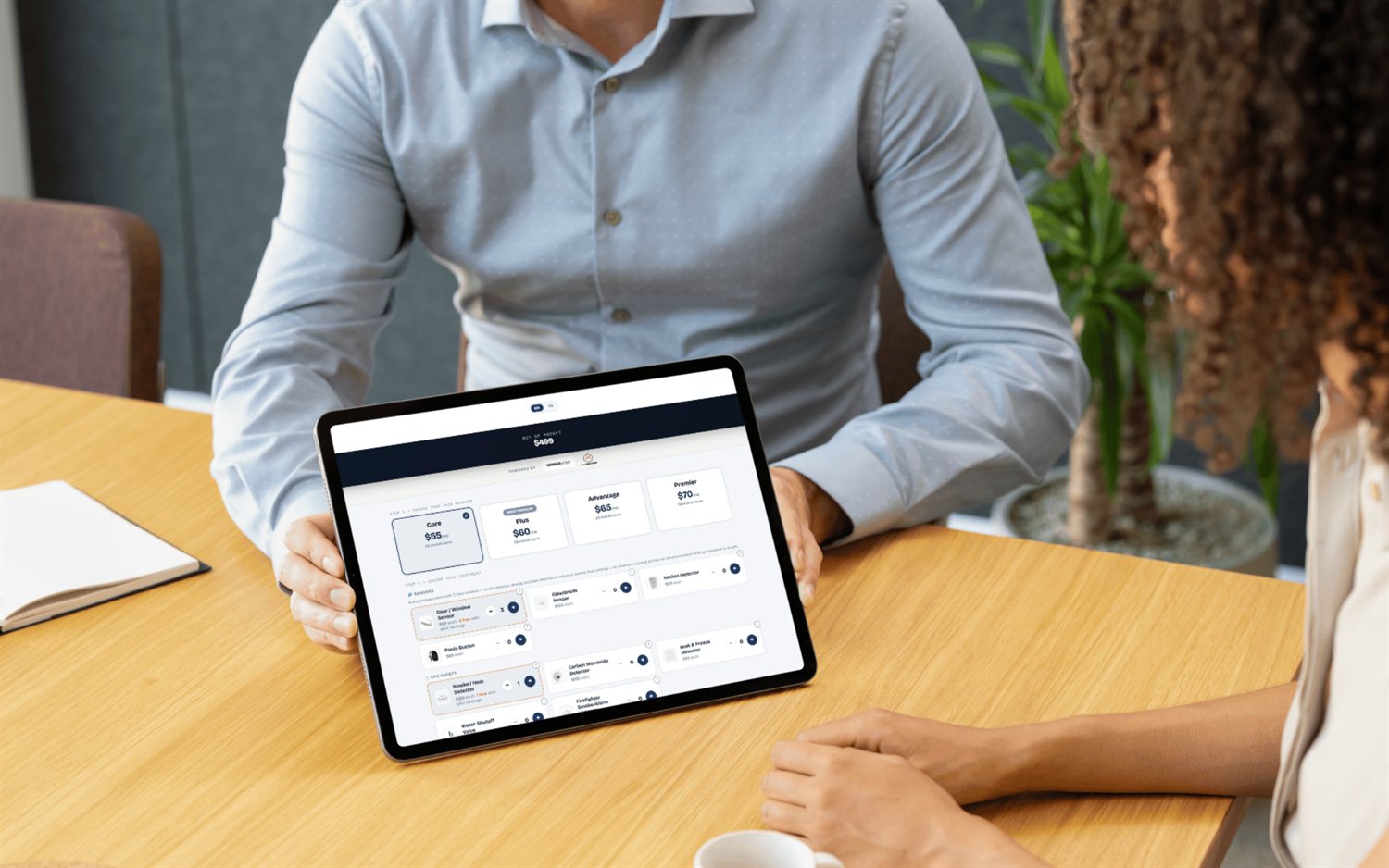 SecurityQS doorstep quote builder on a tablet with monitoring plans, equipment and a live out-of-pocket total